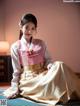 A woman in a pink and white hanbok sitting on the floor.