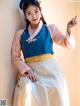 A woman in a blue and pink hanbok is posing for a picture.