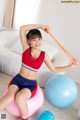 A young girl sitting on an exercise ball holding a resistance band.